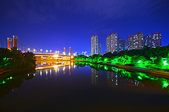 Night cityscape with illuminated bridge and river reflections