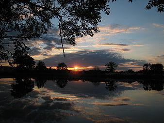 Serene sunset over river with tree silhouettes and reflection