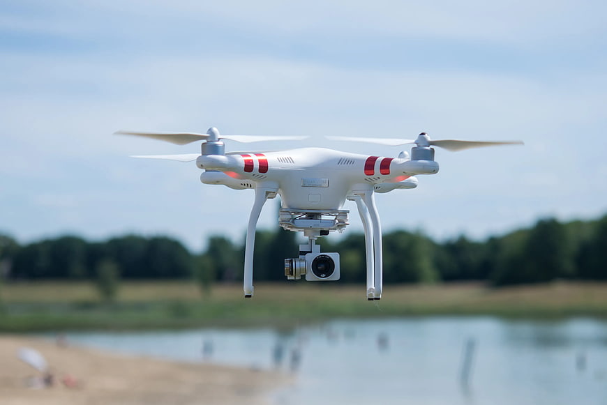 White DJI Phantom Drone Hovering Over Lake