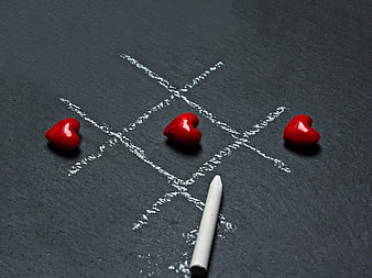 Red hearts winning tic-tac-toe game on slate background