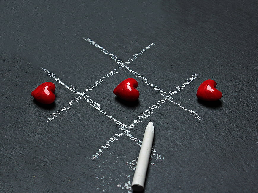 Red hearts winning tic-tac-toe game on slate background