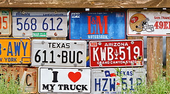 Collection of vintage license plates on wooden fence