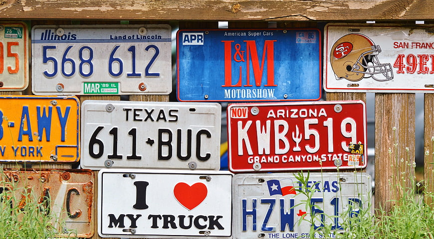 Collection of vintage license plates on wooden fence