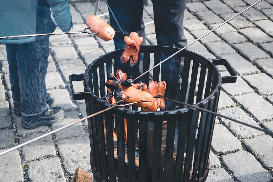 Roasting sausages on skewers over an outdoor fire pit