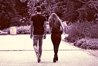 Couple walking away on paved path in park