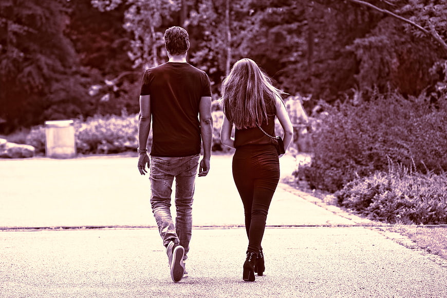Couple walking away on paved path in park
