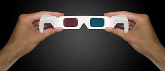 Hands Holding White Anaglyph 3D Glasses Against Dark Background