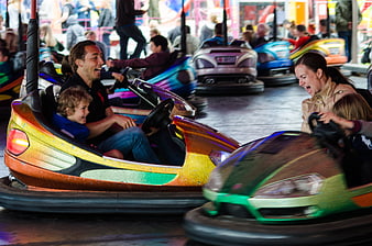 Happy Family Laughing While Riding Bumper Cars at Amusement Park