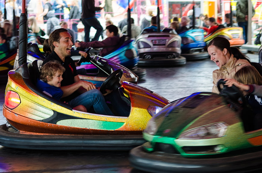 Happy Family Laughing While Riding Bumper Cars at Amusement Park