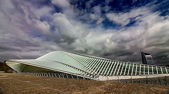 Modern Curved Glass Stadium Architecture Under Dramatic Clouds