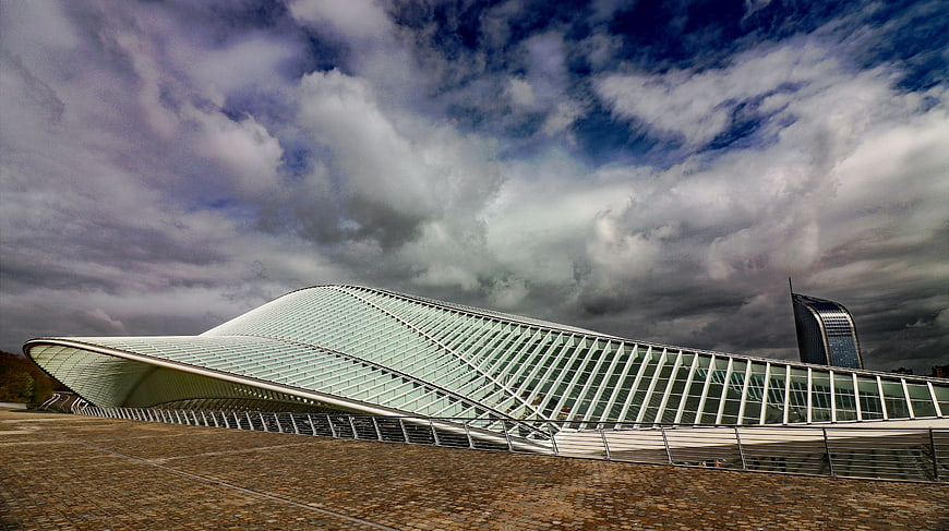 Modern Curved Glass Stadium Architecture Under Dramatic Clouds