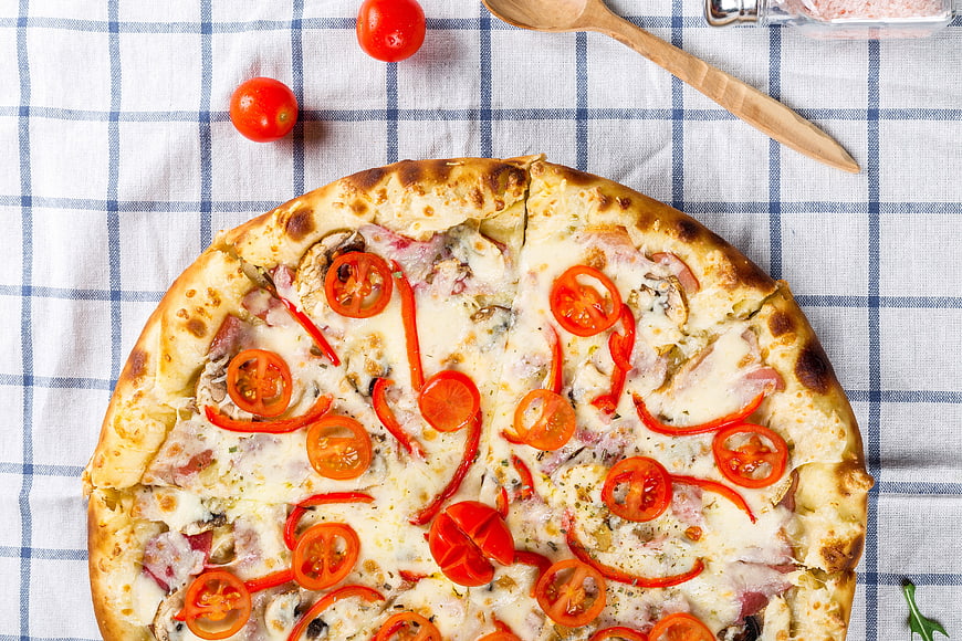 Overhead View of Fresh Pizza with Tomatoes on Checkered Tablecloth
