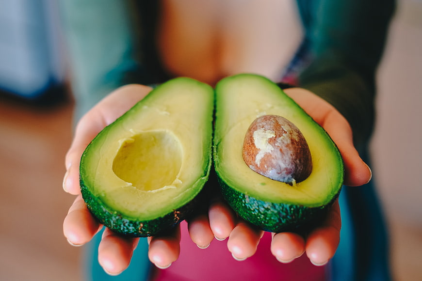 Hands Holding Halved Fresh Avocado
