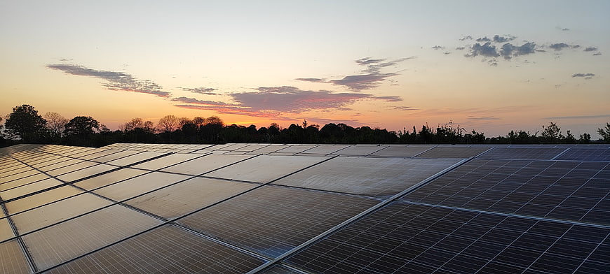 Solar panels on a roof at sunset with orange sky