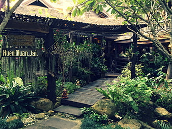 Tropical Garden Entrance with Wooden Walkway and Sign