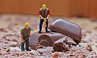 Miniature construction workers mining chocolate bar
