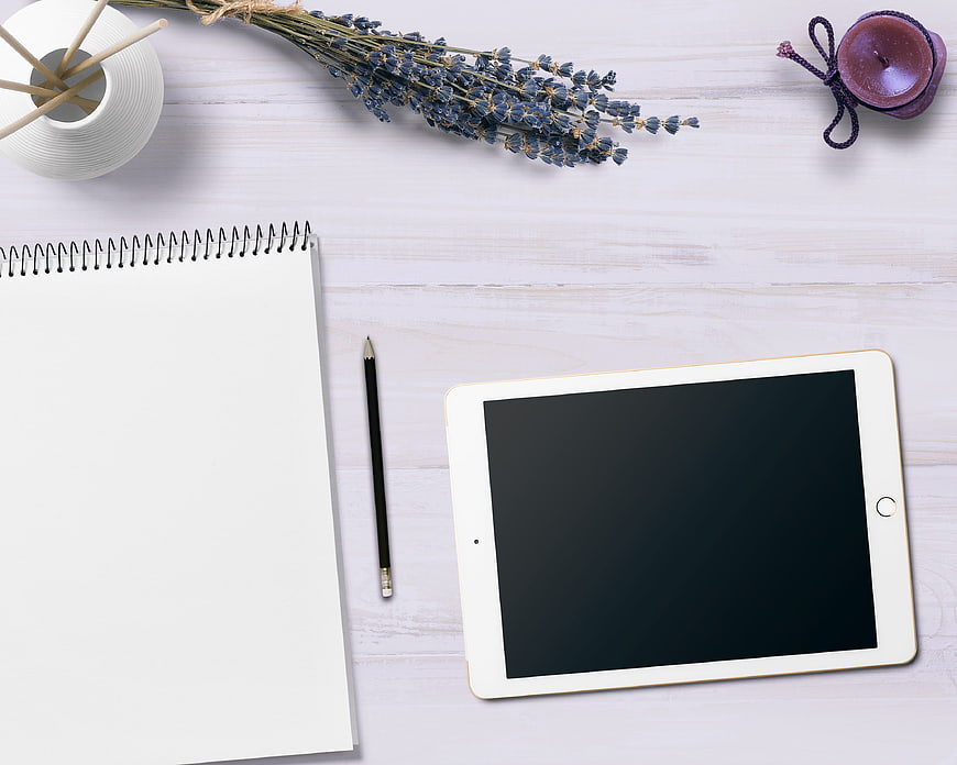Flat lay workspace with tablet, notebook, and lavender
