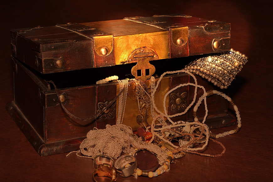 Vintage wooden treasure chest overflowing with antique jewelry and pearls