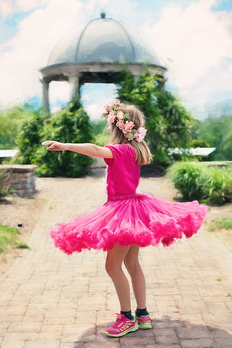 Little girl in pink tutu twirling outdoors