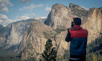 Man taking photo of granite mountains with smartphone