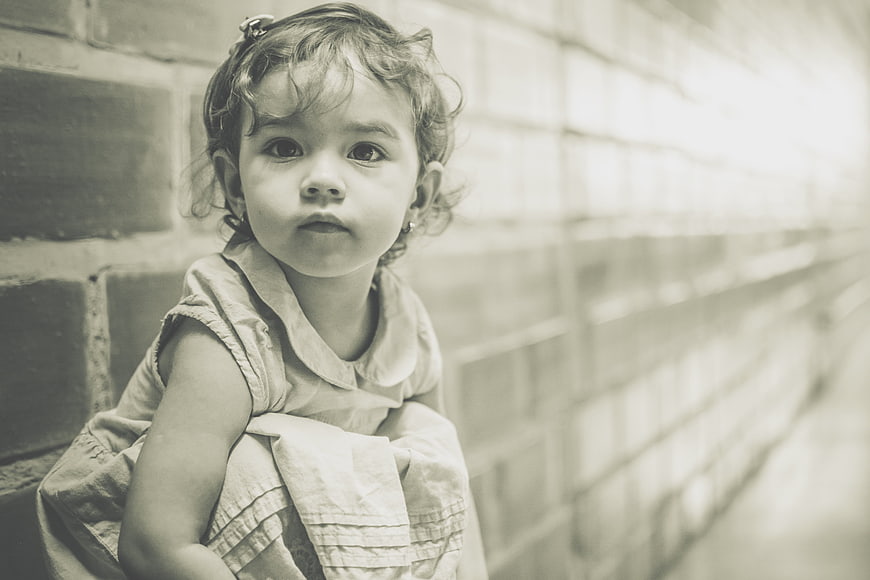 Vintage Portrait of a Young Girl Leaning Against a Brick Wall