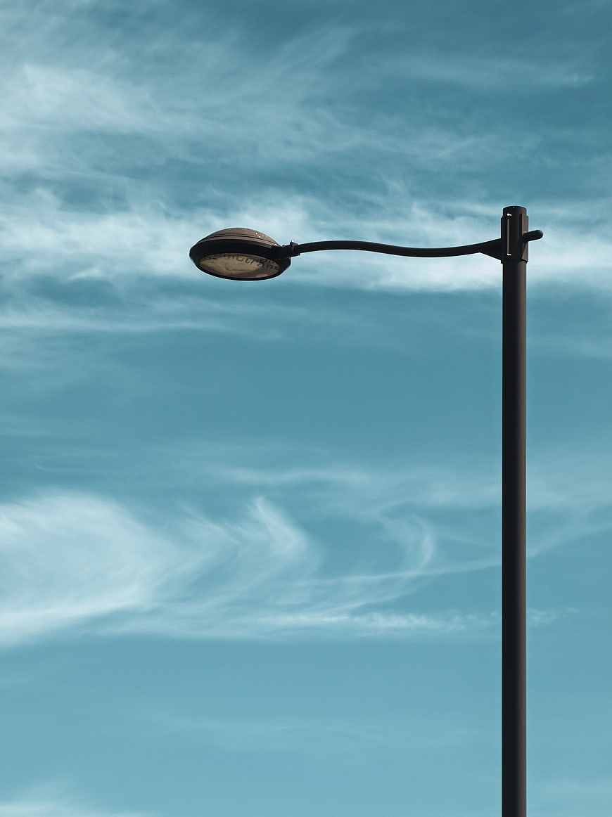 Minimalist street lamp against blue sky with wispy clouds