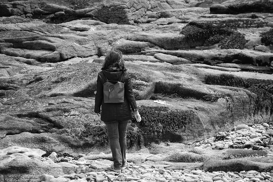 Woman walking on rocky coastal landscape in black and white