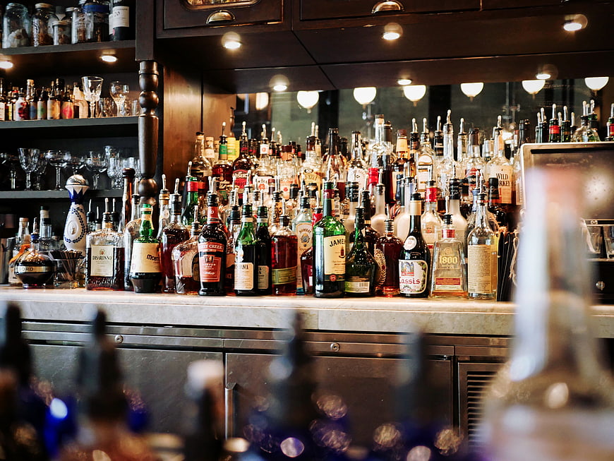 Well-stocked bar counter with liquor bottles and glassware