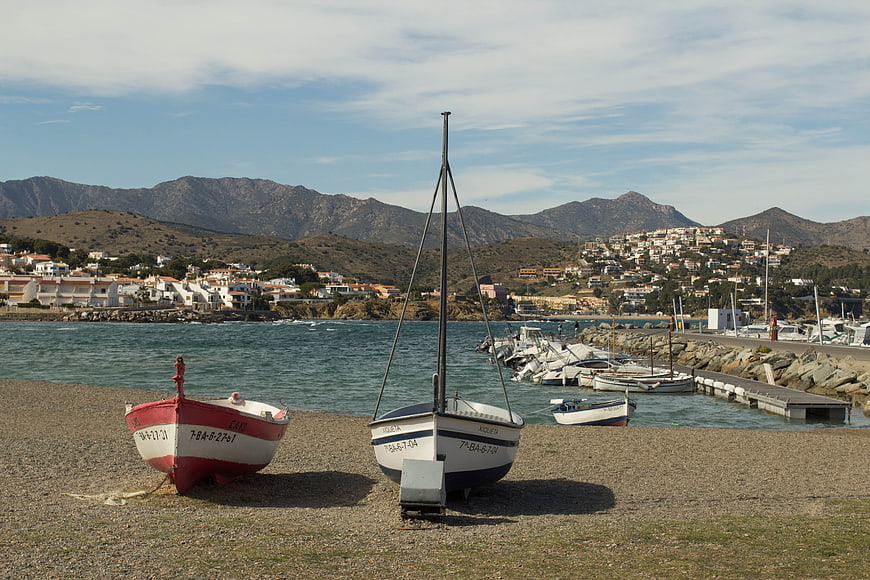 Fishing boats on pebble beach with coastal village and mountains