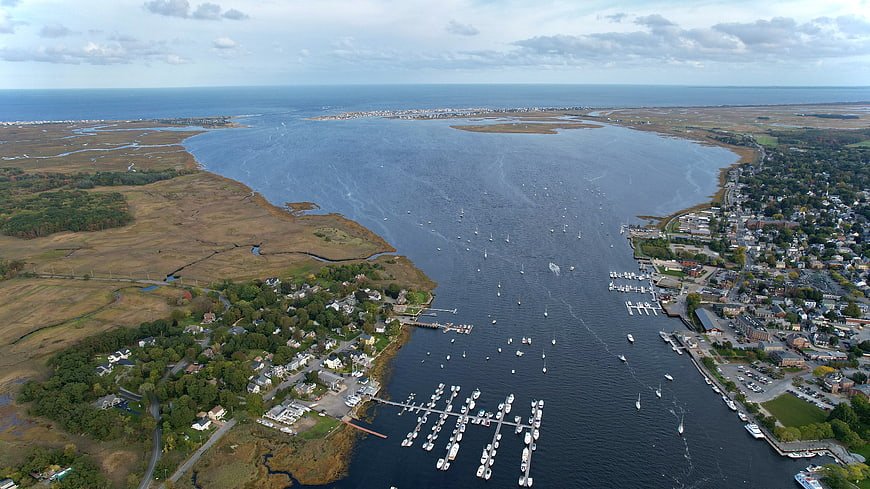 Aerial view of coastal harbor town with boats and marshland