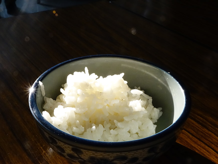 Steaming White Rice in Ceramic Bowl on Wooden Table