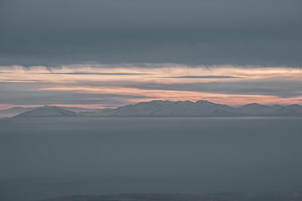 Snowy Mountains Rising Above Sea of Fog at Sunset