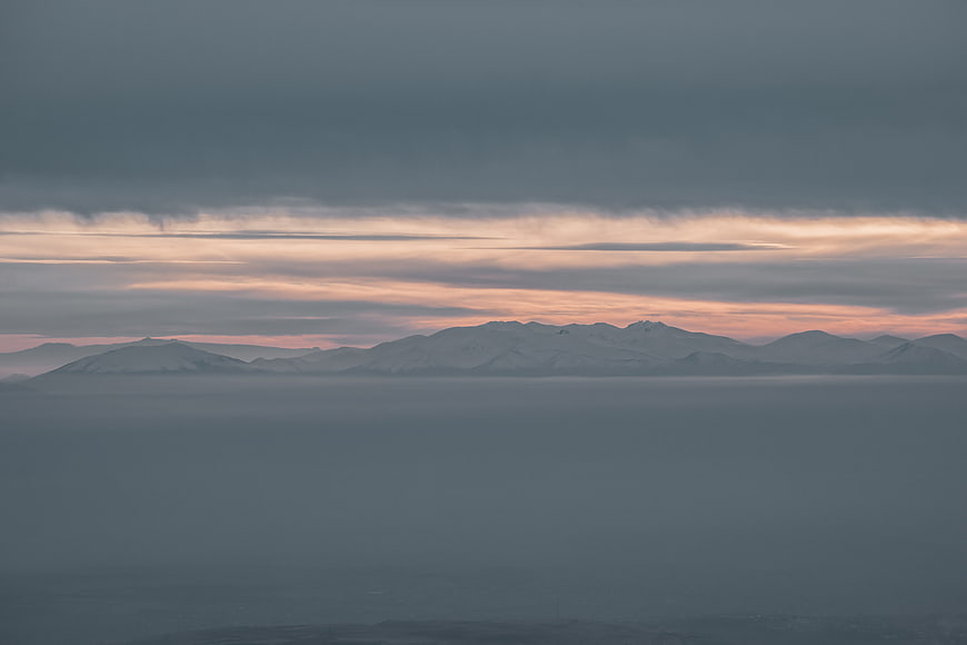 Snowy Mountains Rising Above Sea of Fog at Sunset