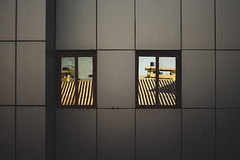 Modern building facade with windows reflecting yellow roof tiles