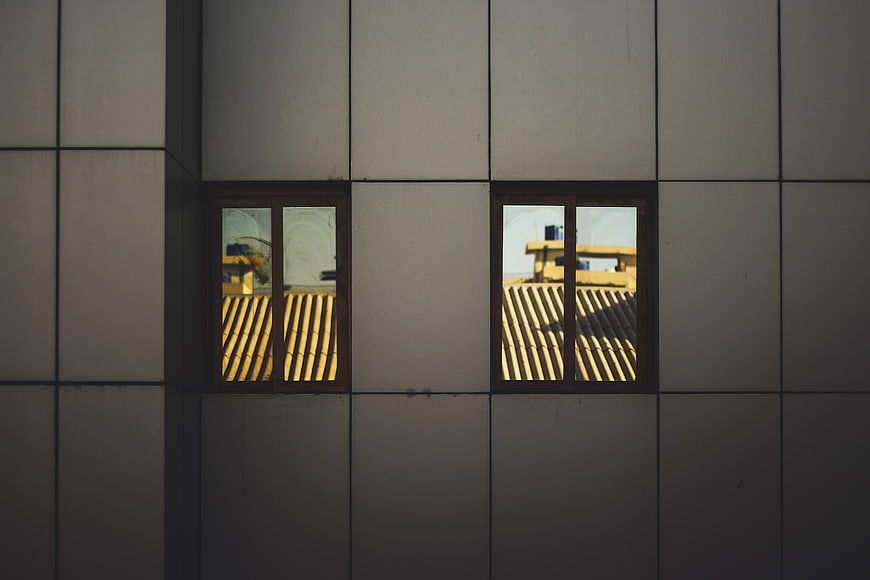 Modern building facade with windows reflecting yellow roof tiles