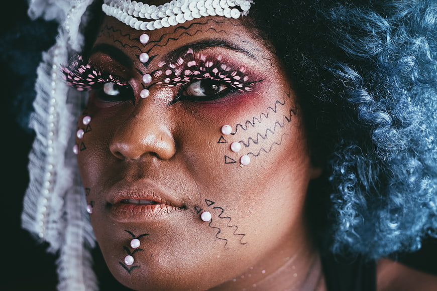 Artistic portrait of woman with elaborate face makeup and pearls
