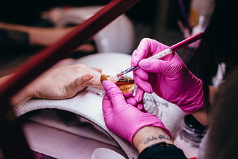Close-up of nail technician applying gel polish with brush