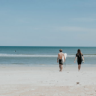 Couple Walking on Beach with Surfboards