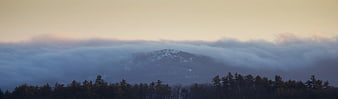 Snowy mountain peak emerging from sea of clouds at sunrise