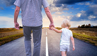 Father and son walking hand in hand on a rural road