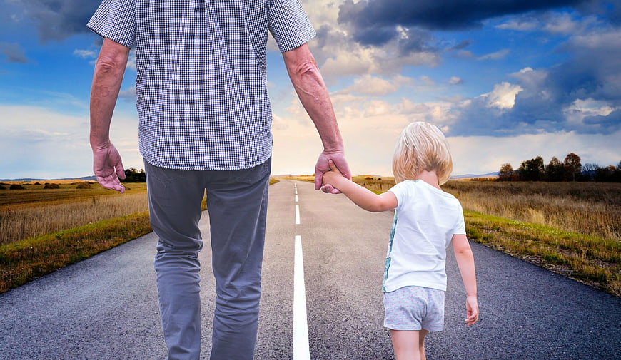 Father and son walking hand in hand on a rural road