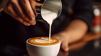 Barista pouring steamed milk into coffee cup for latte art