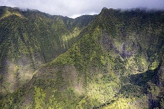 Lush green mountain ridges with clouds and mist