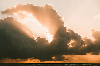 Dramatic sunset with sun rays breaking through clouds over the ocean