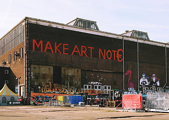 Industrial building with large red graffiti text and street art