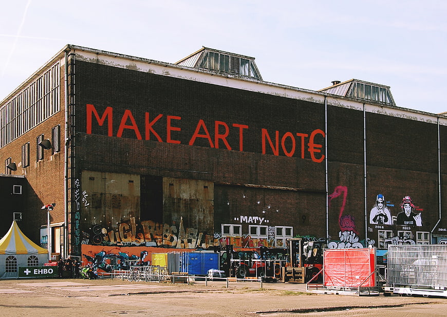 Industrial building with large red graffiti text and street art