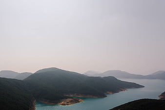 Misty Mountain Landscape with Turquoise Reservoir and Hazy Sky