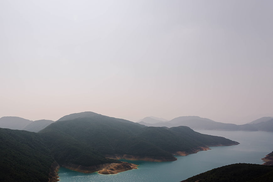 Misty Mountain Landscape with Turquoise Reservoir and Hazy Sky