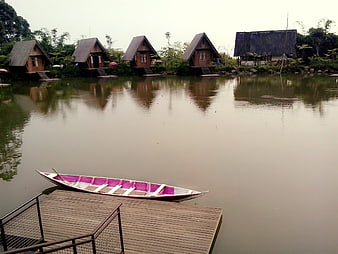 Traditional Wooden Cabanas On A Calm Lake With A Moored Boat