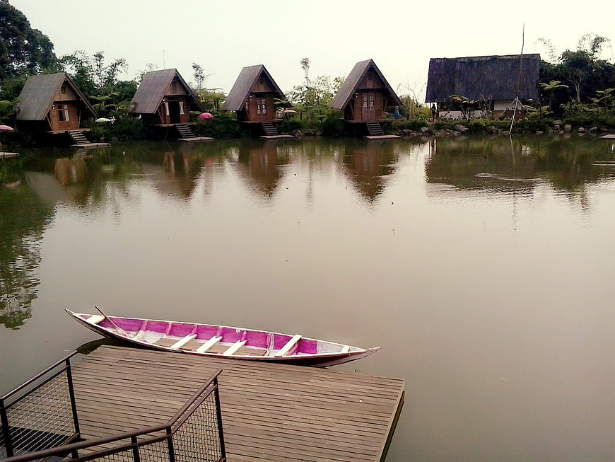 Traditional Wooden Cabanas On A Calm Lake With A Moored Boat